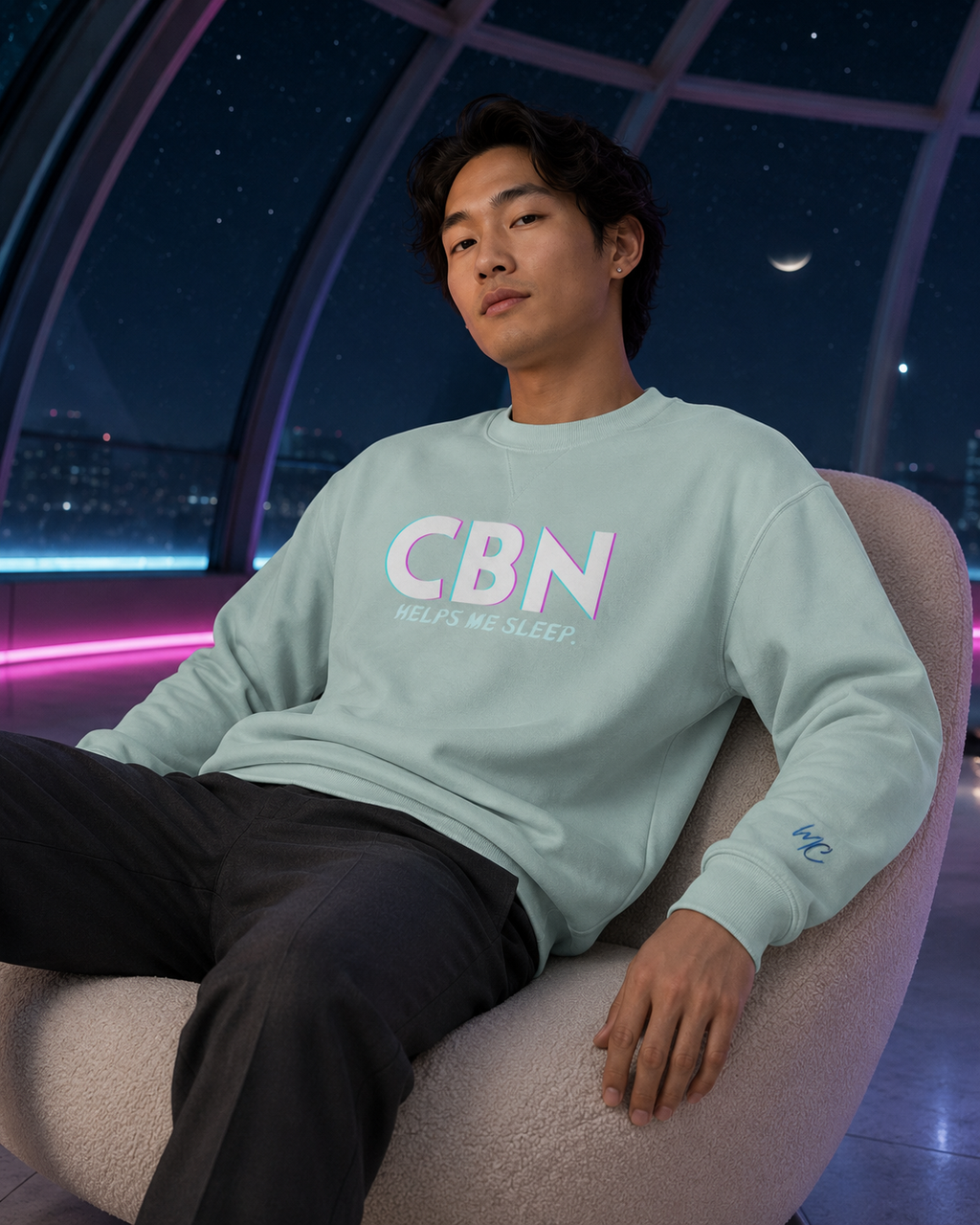 Man wearing an agave CBN Helps Me Sleep premium sweatshirt with a blue MC sleeve logo in a moonlit observatory lounge.