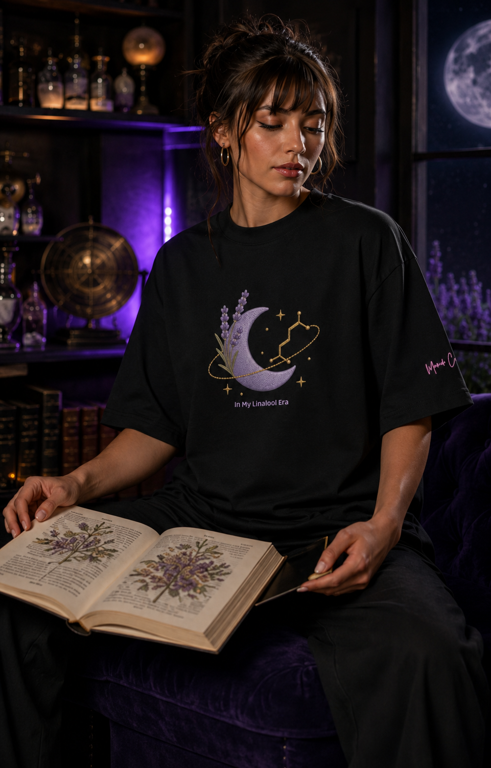 Woman wearing the black In My Linalool Era oversized tee while reading a botanical book in a moonlit apothecary.