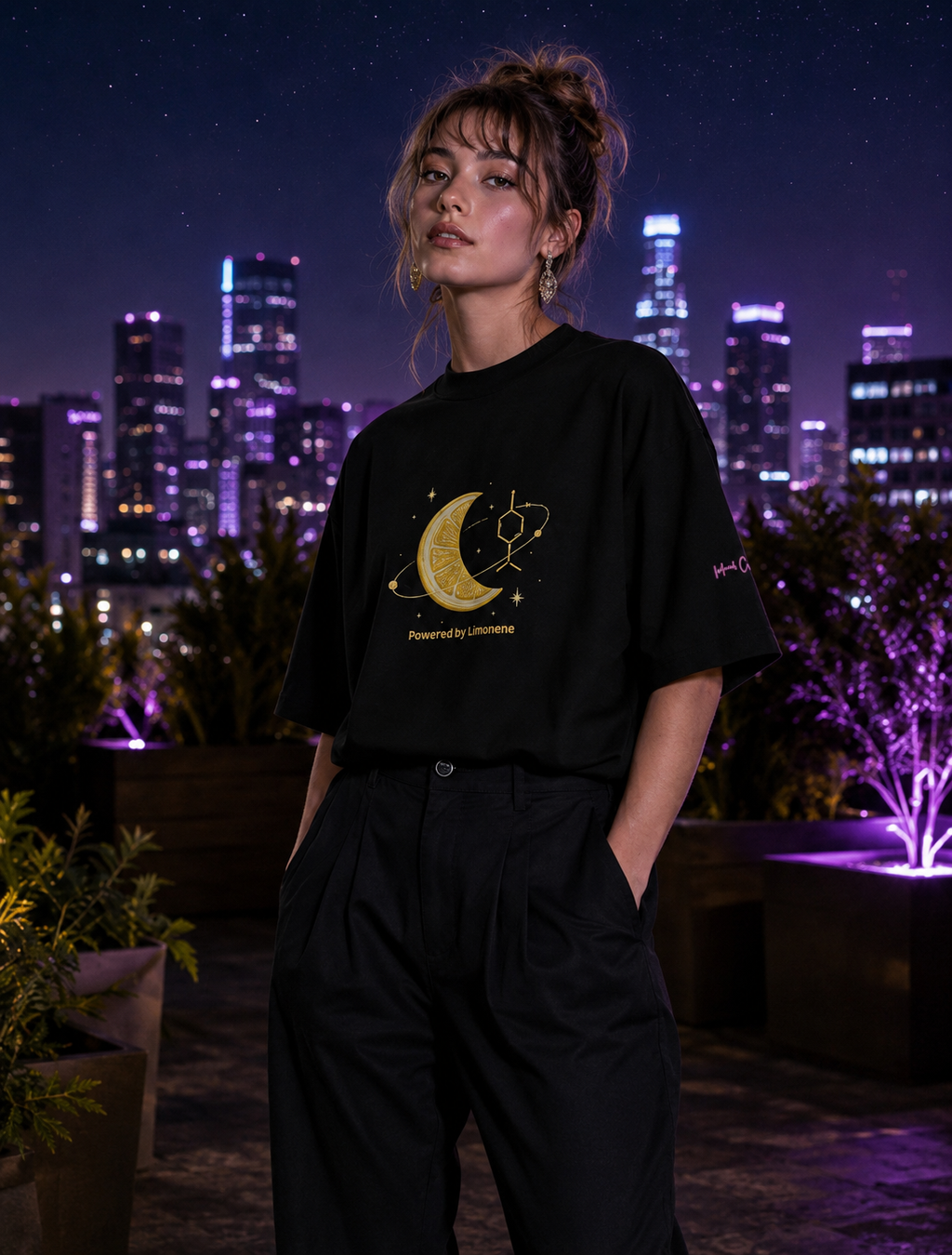 Woman wearing the black Powered by Limonene oversized tee in an ultraviolet rooftop garden overlooking the city.