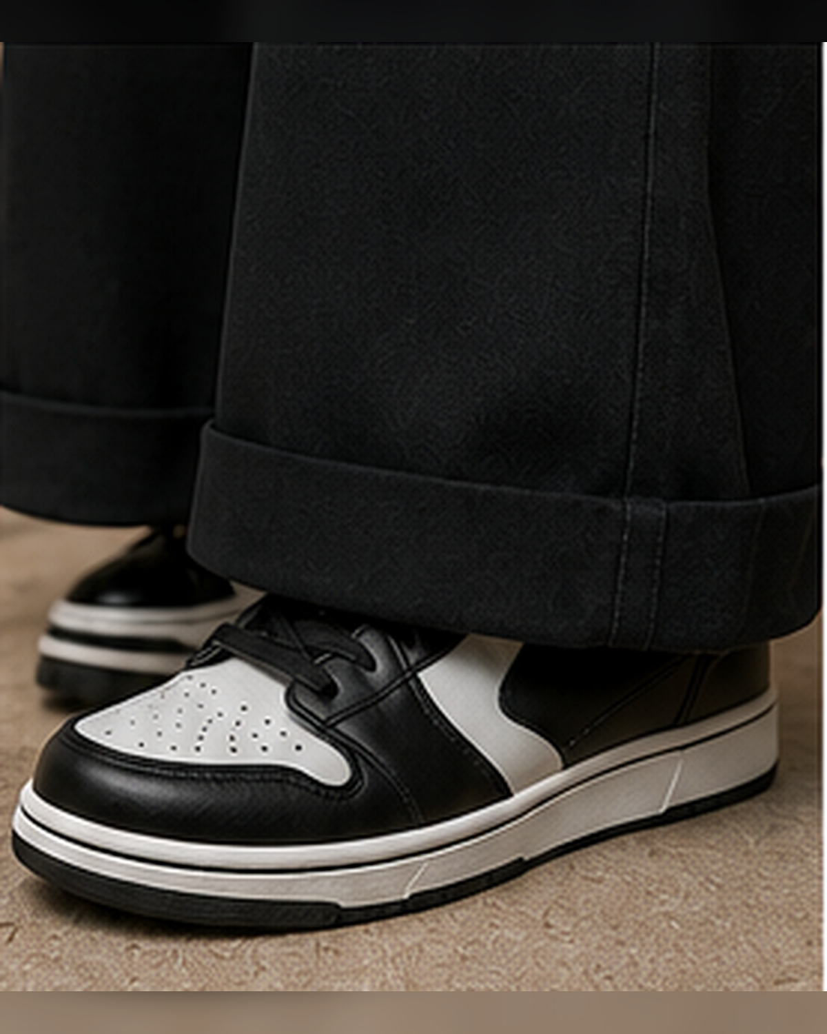 Close-up lifestyle view of black Mandi Cruz Media wide-leg trousers styled with black and white sneakers, highlighting the relaxed hem and drape.