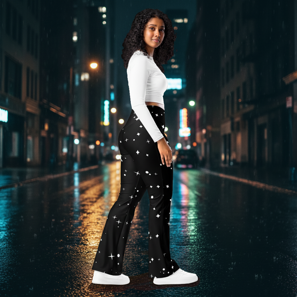 Woman wearing black celestial-print flare leggings with a white crop top and sneakers on a neon-lit city street at night.