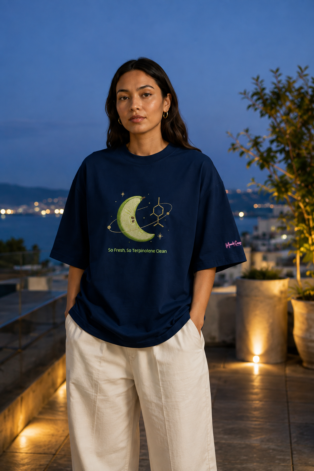 Woman wearing the French-navy So Fresh, So Terpinolene Clean oversized tee on a coastal rooftop at blue hour.
