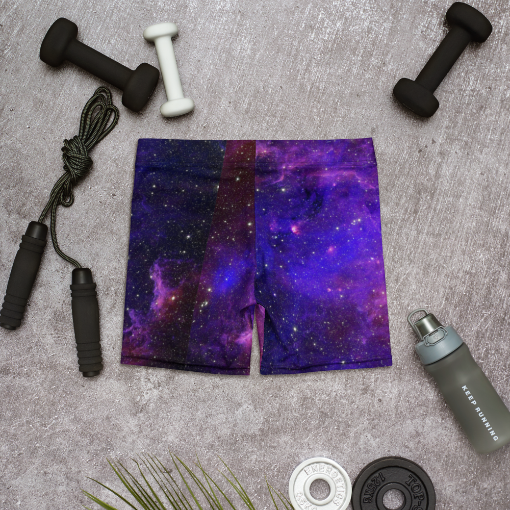 Purple galaxy-print yoga shorts arranged with dumbbells, a jump rope, water bottle and weight plates.