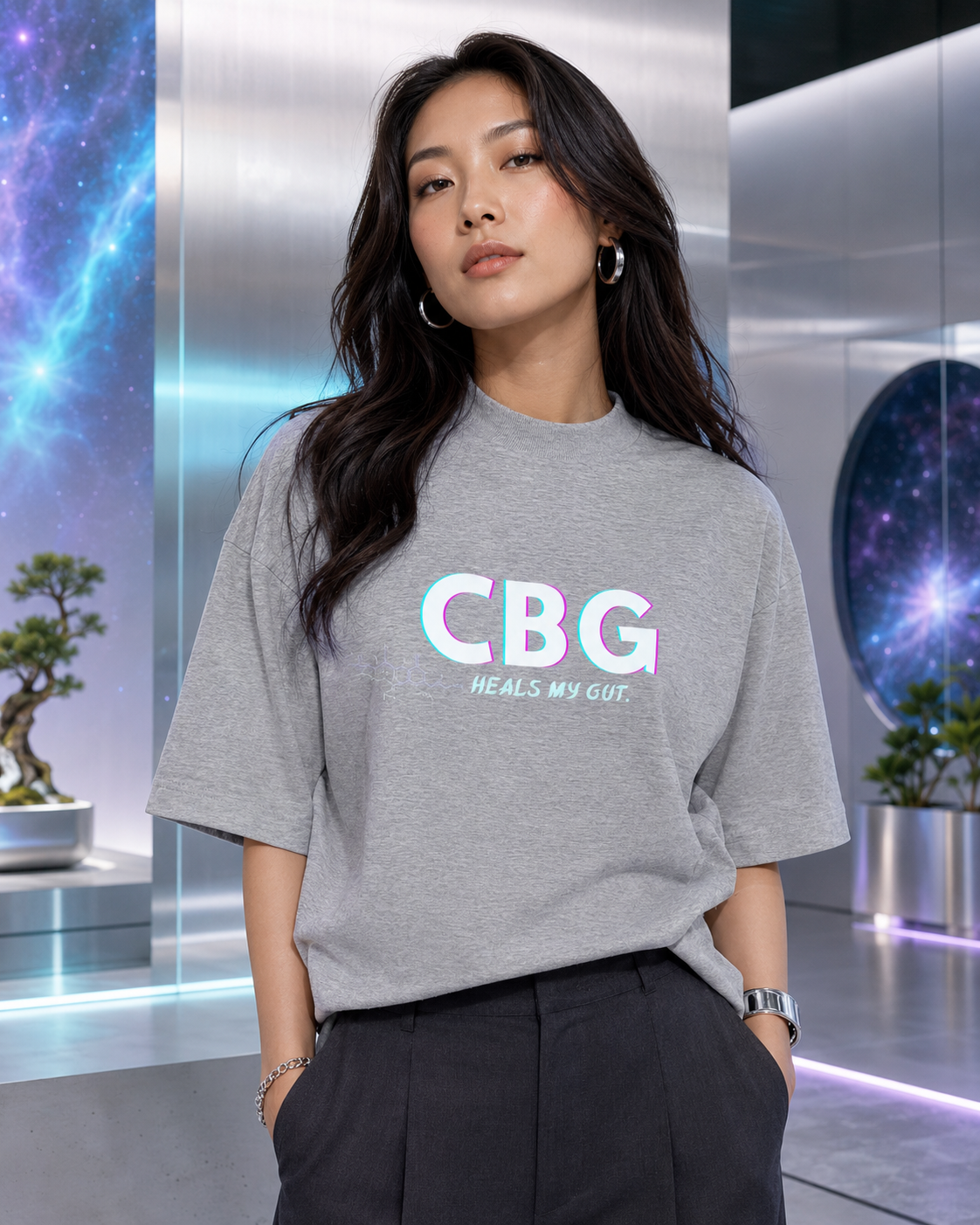 Woman wearing the Heather Grey CBG Heals My Gut oversized organic tee in a silver futuristic gallery.