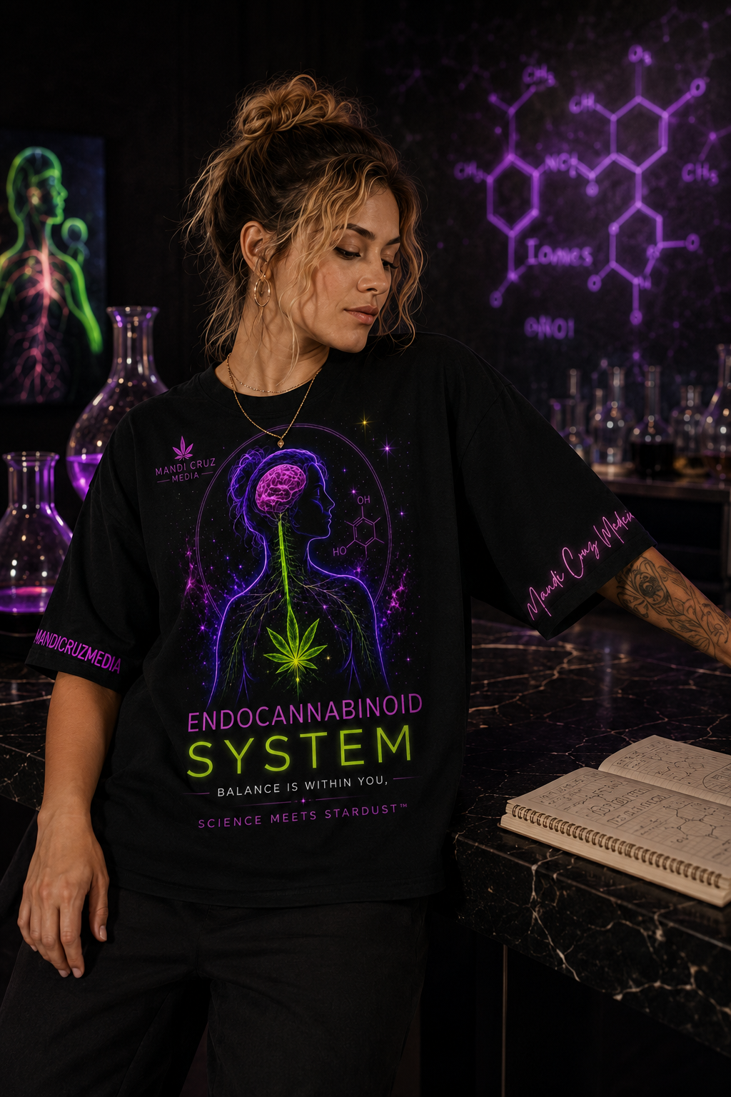 Woman wearing the Endocannabinoid System oversized tee beside a black marble science workspace and notebook.