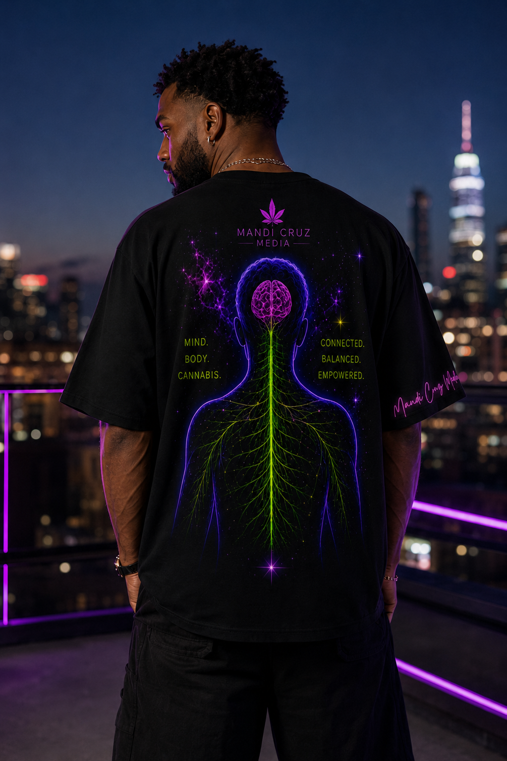 Man wearing the back of the black oversized tee featuring neon brain, spine and nervous system artwork on a rooftop