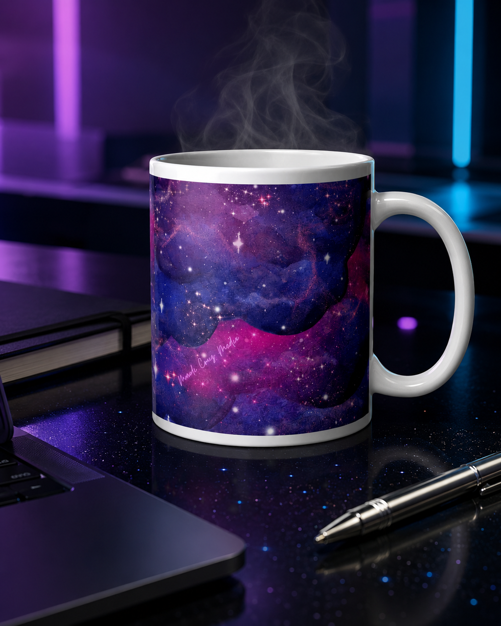Steaming Large Nebula Mug beside a dark laptop, journal and silver pen on a violet-and-cyan illuminated workspace.