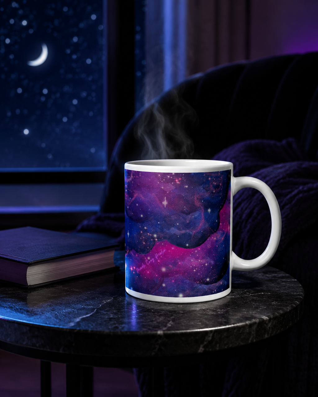 Steaming Large Nebula Mug beside a closed book in a moonlit reading nook, showing its indigo, violet and magenta galaxy wrap.