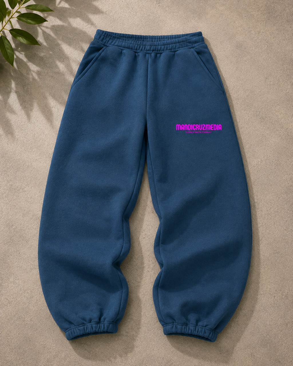 Blue oversized fleece sweatpants by Mandi Cruz Media shown from the front with hot pink Mandi Cruz Media branding on the thigh.