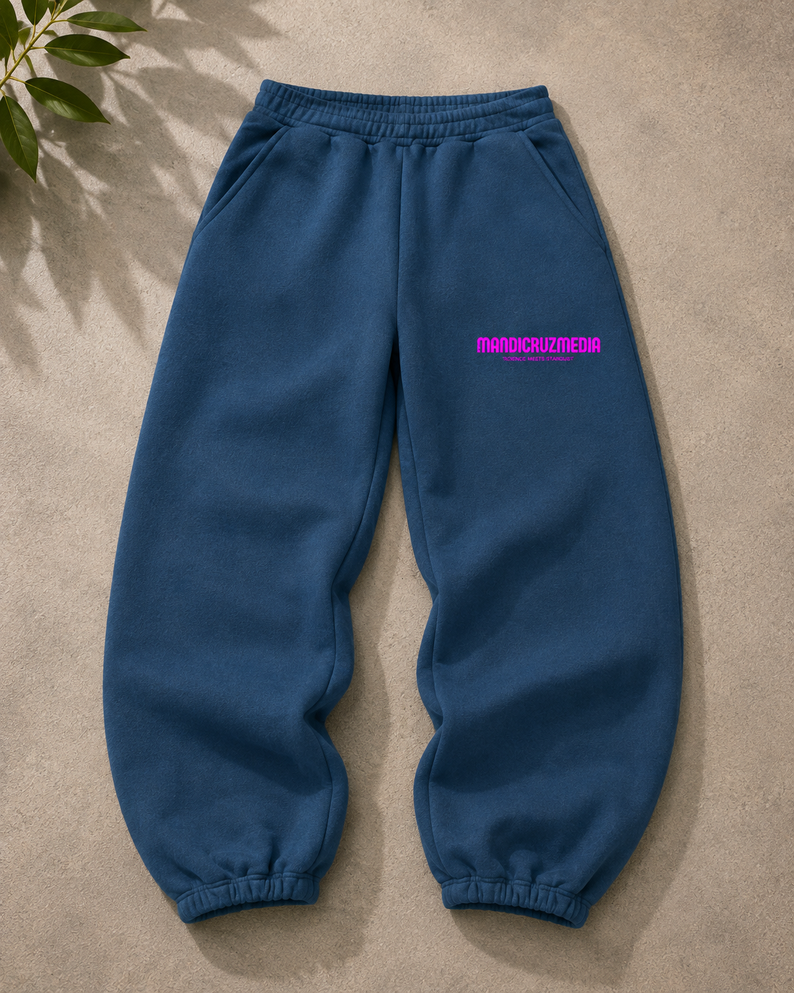 Blue oversized fleece sweatpants by Mandi Cruz Media shown from the front with hot pink Mandi Cruz Media branding on the thigh.
