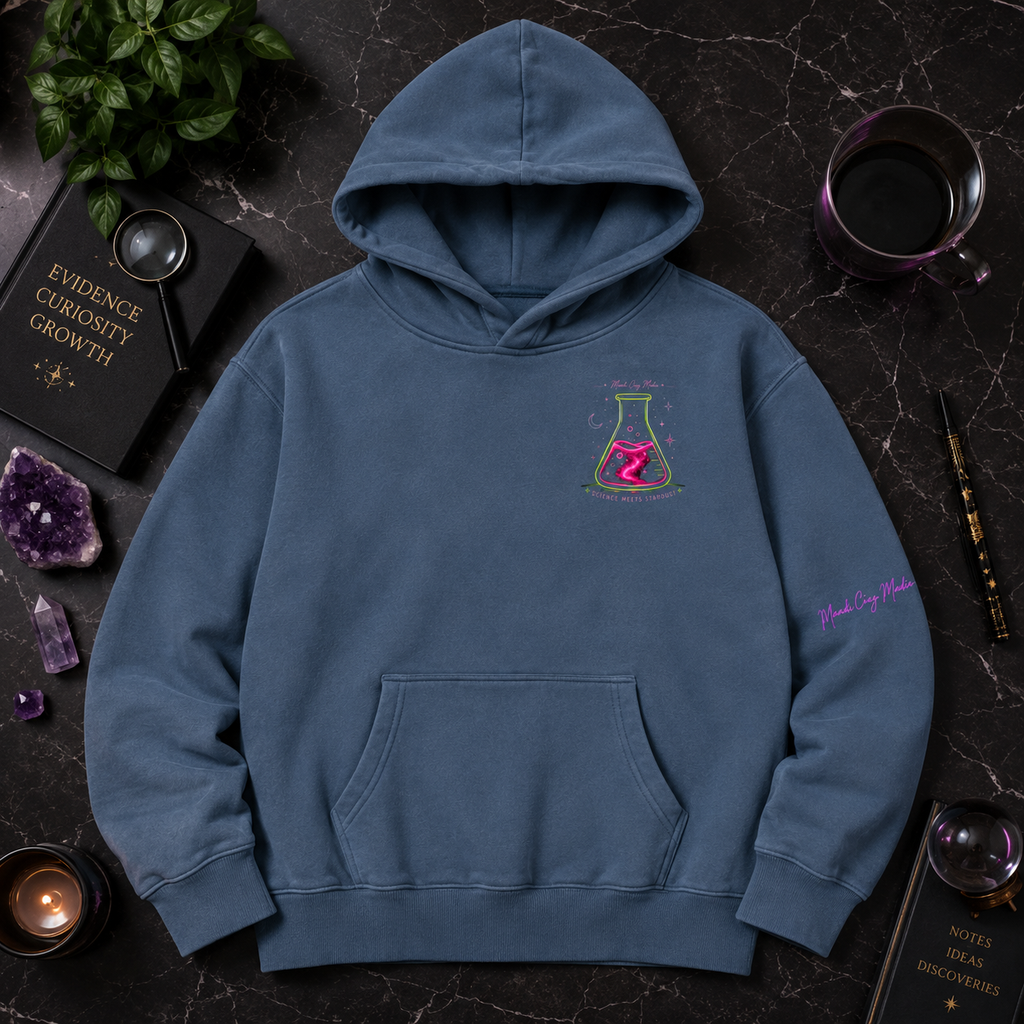 Blue Mandi Cruz Media hoodie shown from the front with neon flask chest graphic and sleeve detail, styled with crystals, greenery, journal and dark celestial accessories.