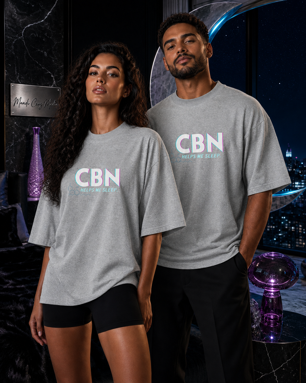 Woman and man modeling matching Heather Grey CBN Helps Me Sleep oversized tees in a celestial bedroom