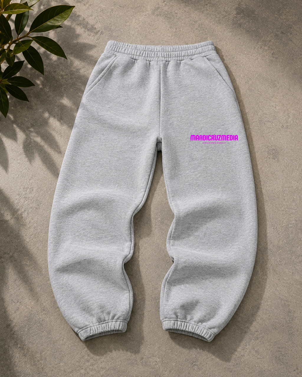 Heather gray oversized fleece sweatpants by Mandi Cruz Media shown from the front with hot pink Mandi Cruz Media logo on the thigh.