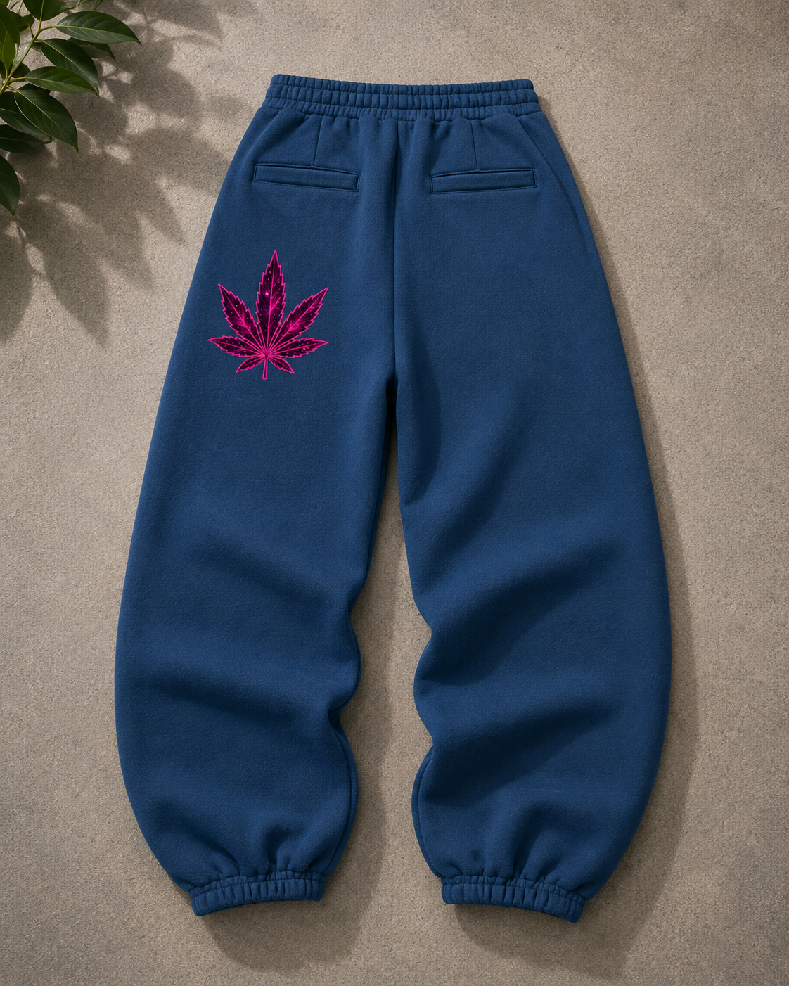 Back flat lay of navy Mandi Cruz Media oversized fleece sweatpants featuring a pink galactic leaf graphic on the left leg, elastic waistband, back welt pockets and elastic cuffs.