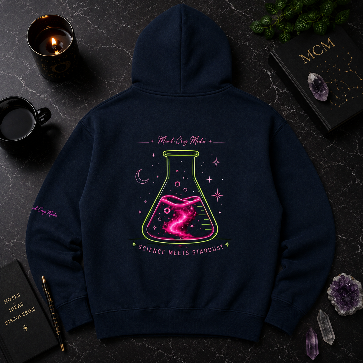 Navy Mandi Cruz Media hoodie shown from the back with oversized neon pink and green flask artwork and Science Meets Stardust lettering in a premium cosmic flat lay.