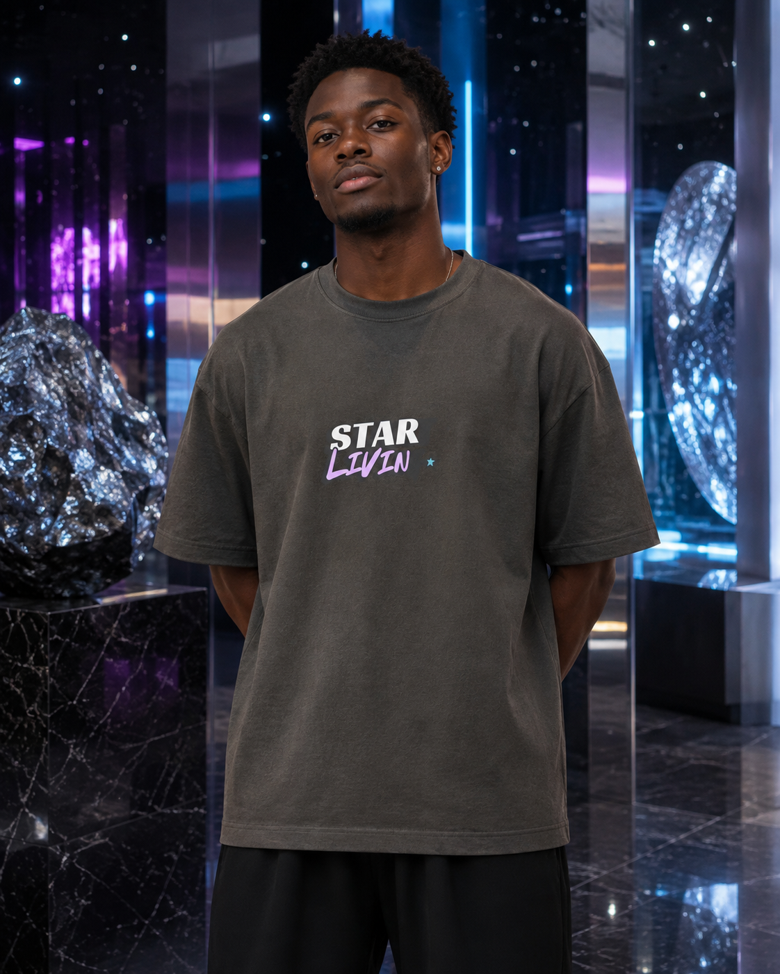 Man wearing the washed-charcoal Start Living oversized tee inside a silver and violet cosmic gallery.