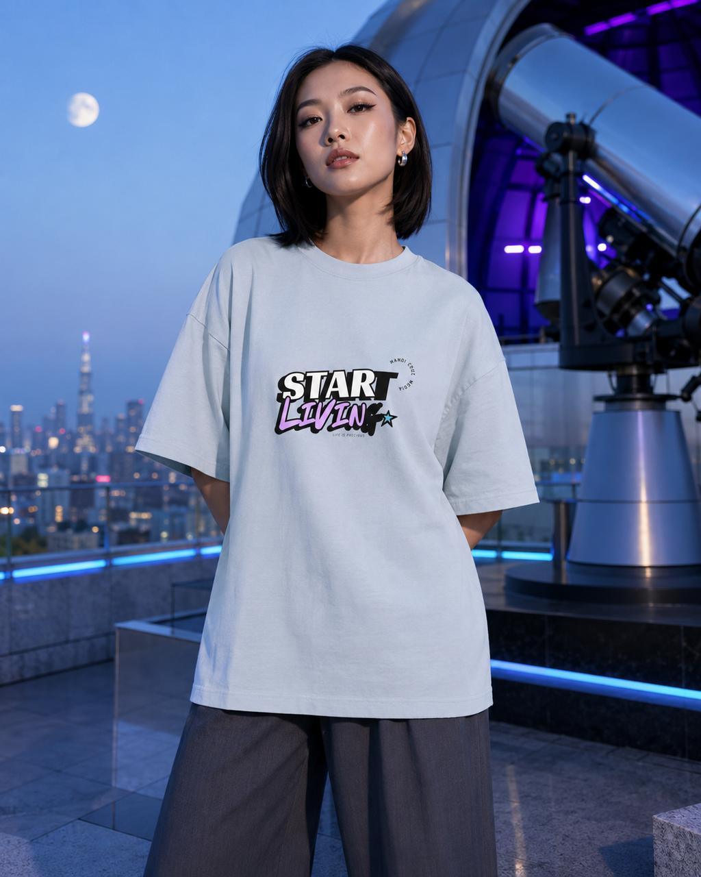 Woman modeling the light washed denim Start Living oversized tee at a moonlit rooftop observatory.