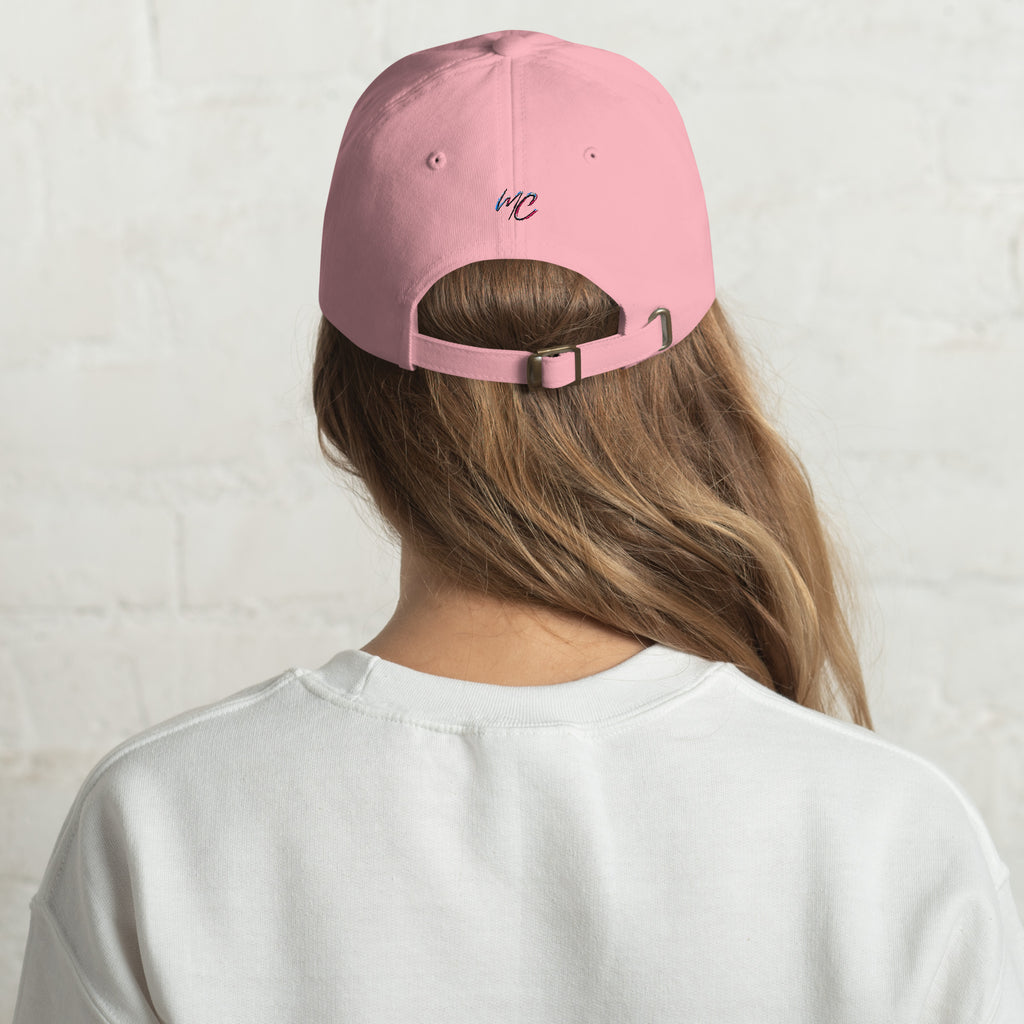 Blonde woman photographed from behind wearing the pink dad hat with its adjustable strap and small MCM embroidery visible.