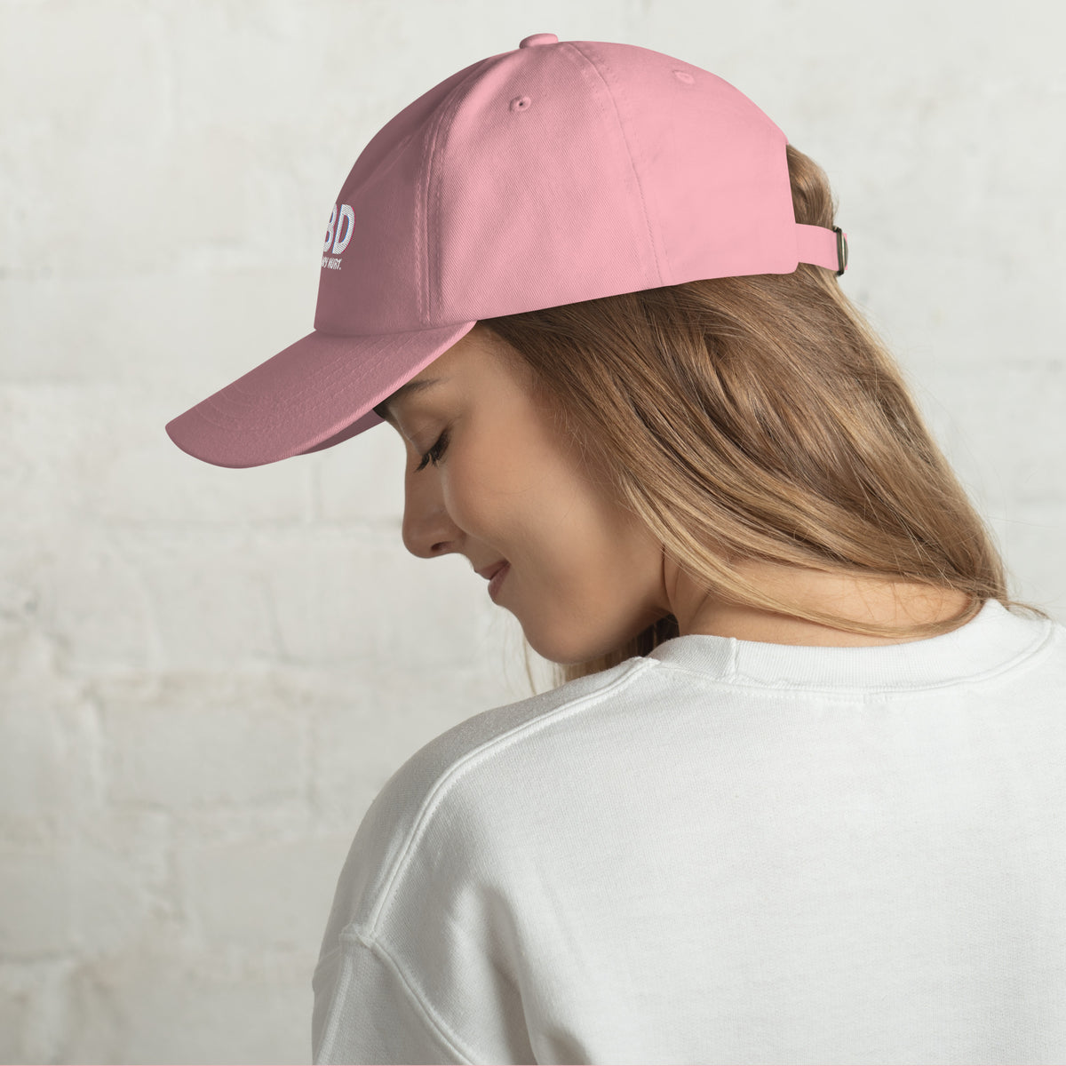 Blonde woman looking downward in a side-profile pose while wearing the pink CBD Heals My Hurt dad