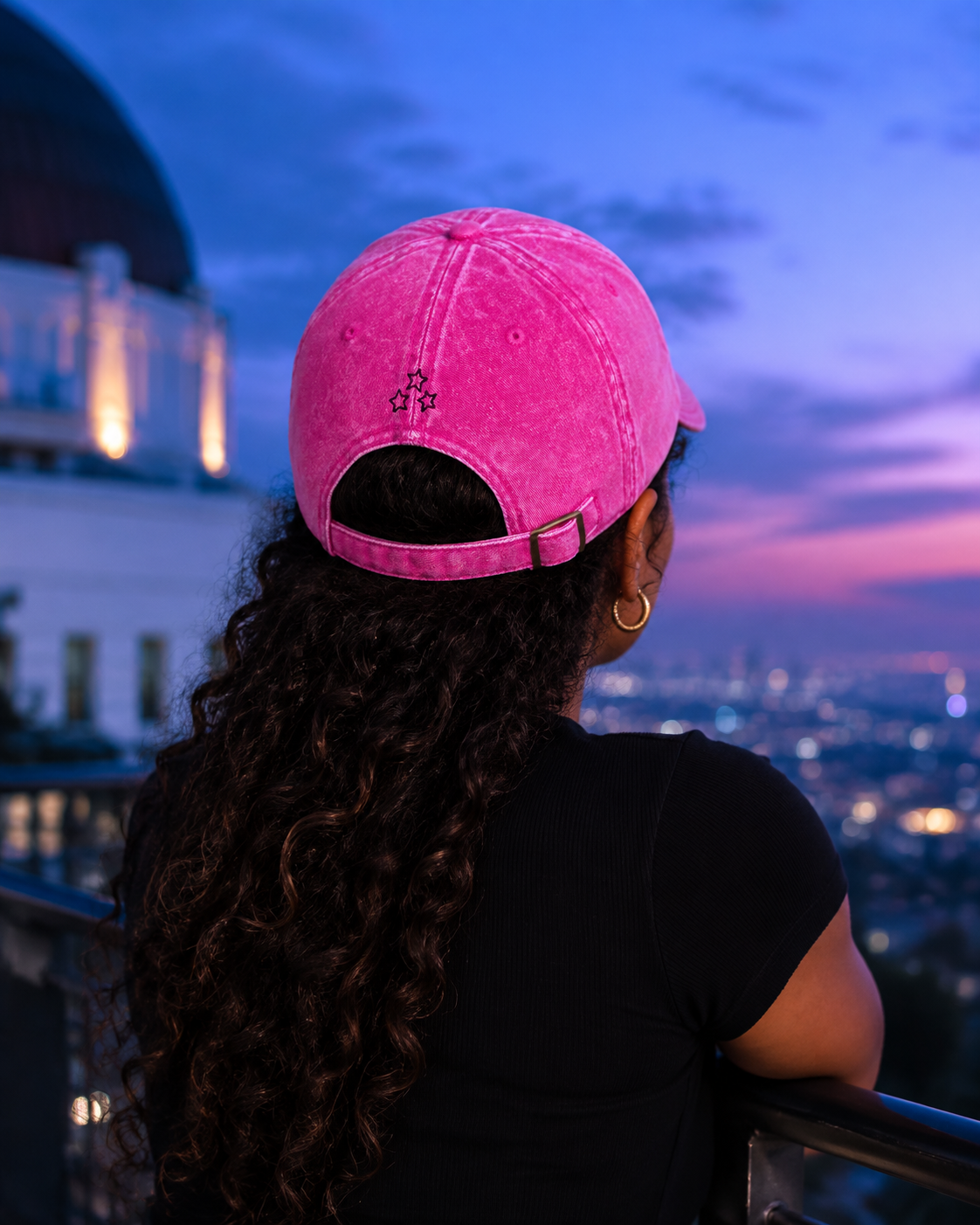 Rear view of a woman wearing the pink vintage cap, showing three embroidered stars and an adjustable strap.