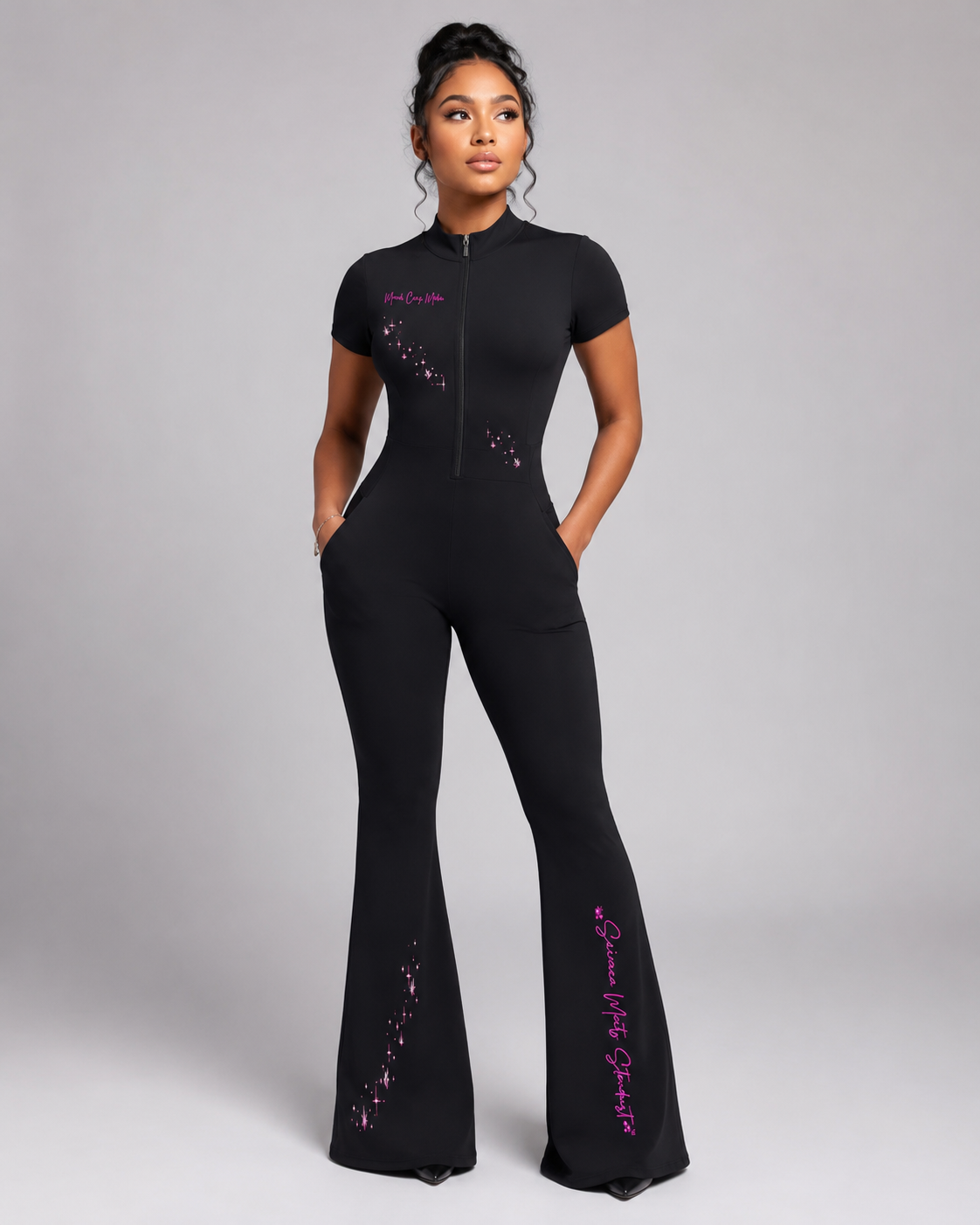 Model wearing the black fitted quarter-zip jumpsuit with pockets, flared legs, pink celestial graphics, and Science Meets Stardust script.