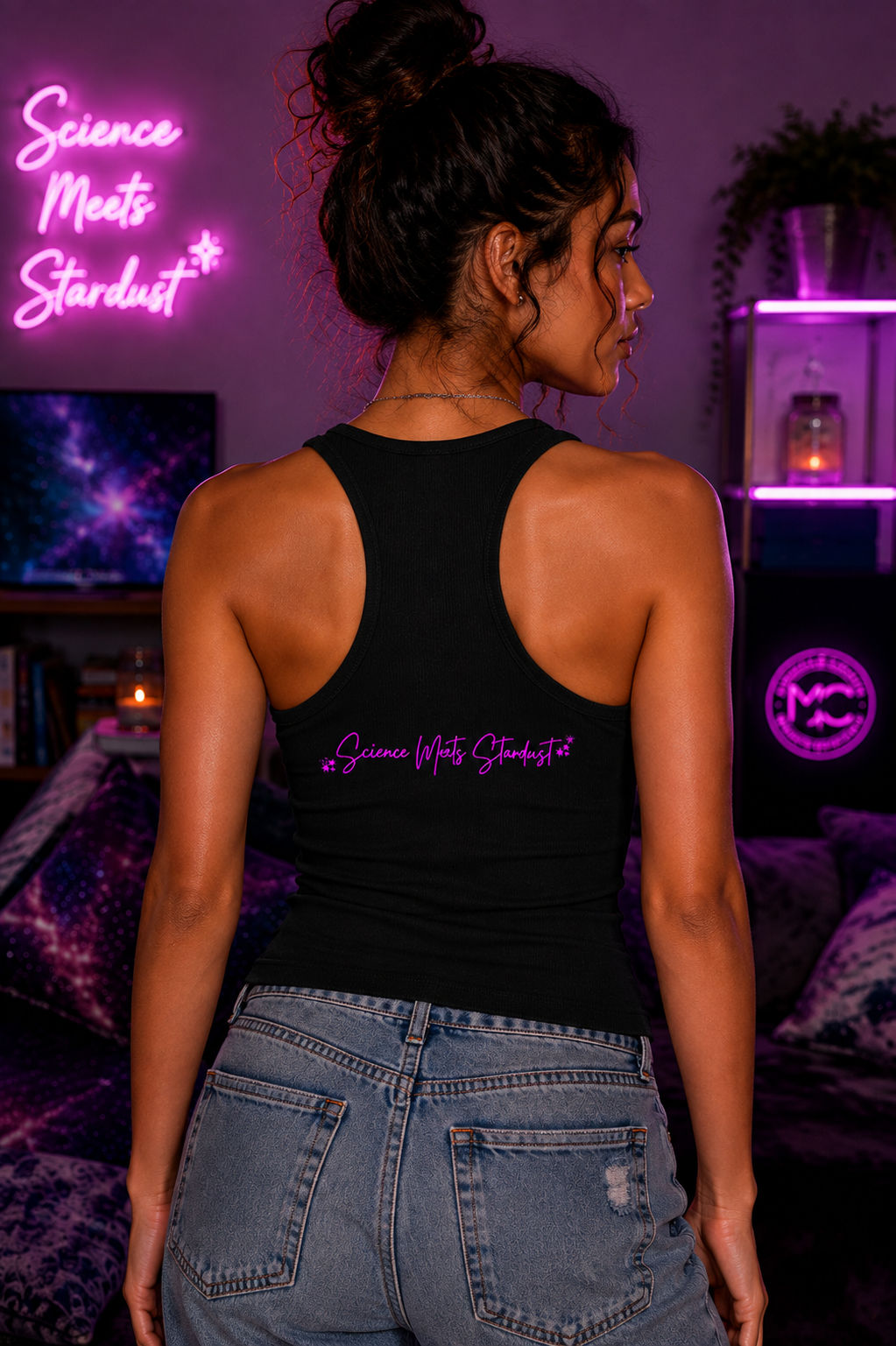 Back view of woman wearing black ribbed racerback tank featuring pink Science Meets Stardust script in a cosmic Mandi Cruz Media setting.