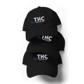 Front product view of the black dad hat featuring the embroidered THC Helps Me Live design by Mandi Cruz Media.