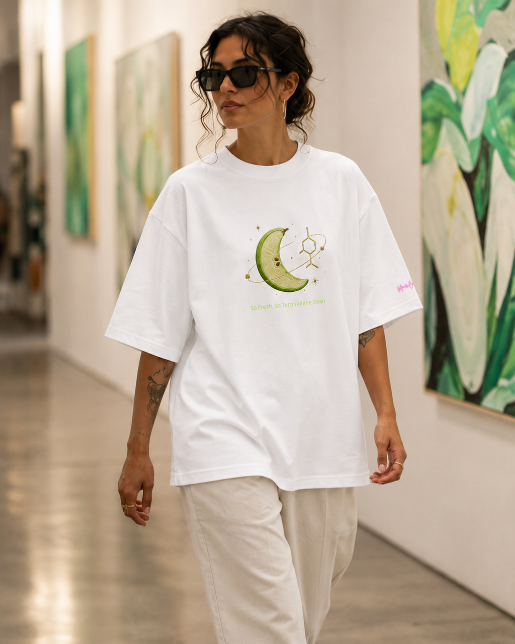 Woman wearing the white So Fresh, So Terpinolene Clean oversized tee while walking through a contemporary gallery.