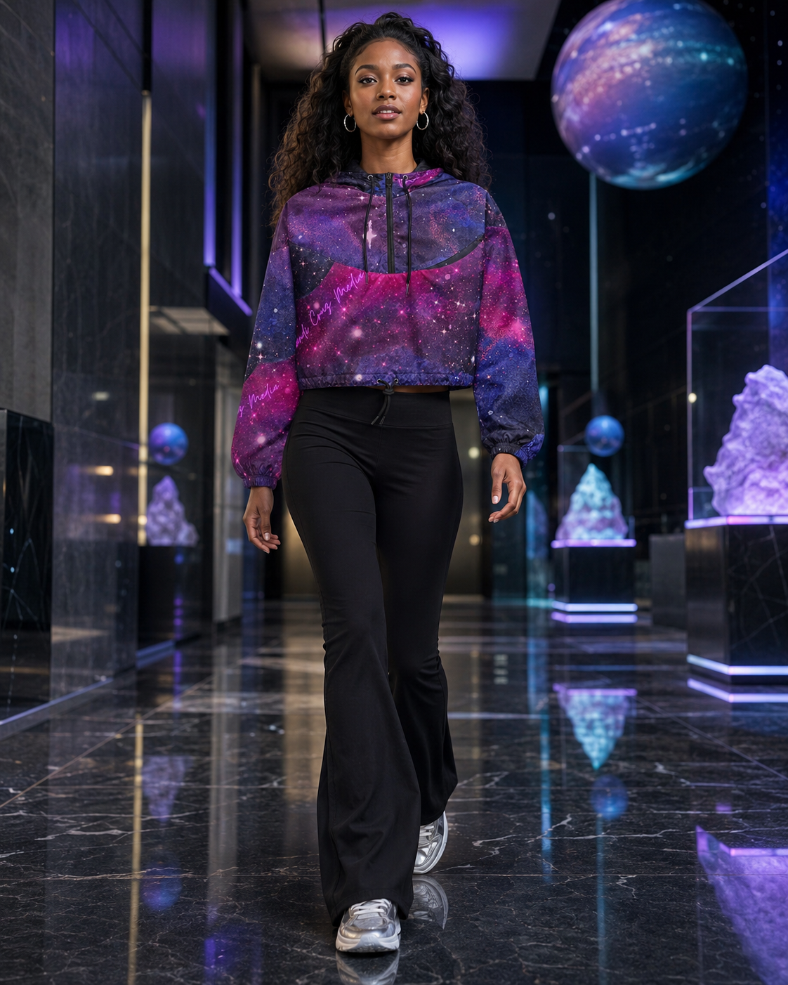 Full-body view of a woman wearing the galaxy cropped windbreaker and black flared pants inside a futuristic celestial gallery.