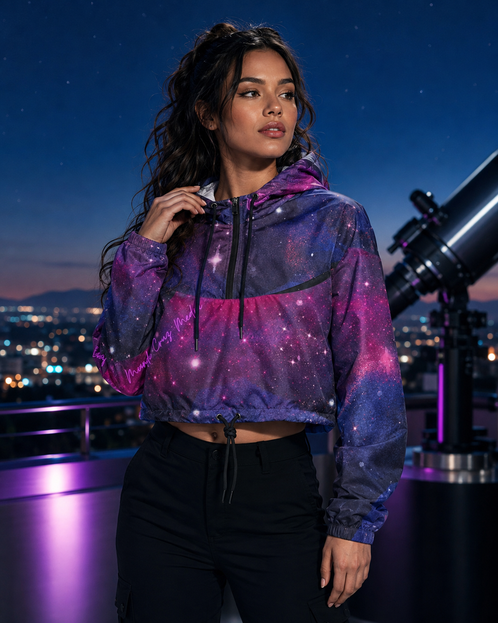 Woman wearing the Mandi Cruz Media galaxy cropped windbreaker at a rooftop observatory with violet lighting and a telescope.