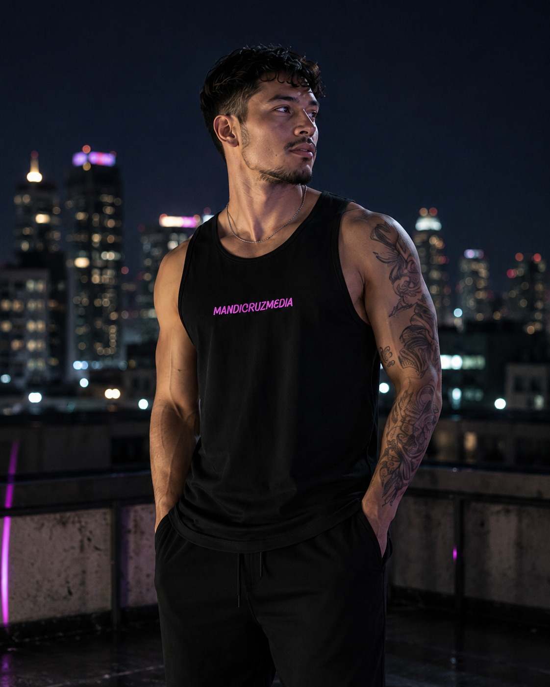 Male model wearing the black Mandi Cruz Media premium tank on a city rooftop at night.
