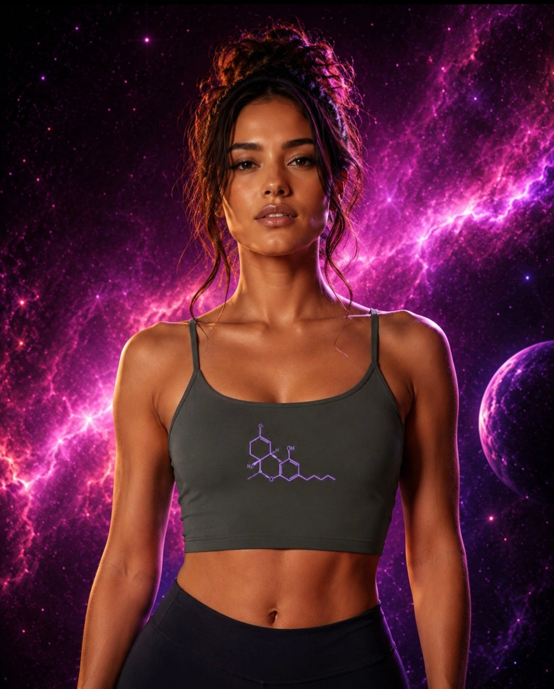 Front lifestyle view of a woman wearing the Dark Gray Neon THC Molecule Crop Tank featuring a purple THC molecular structure graphic against a vibrant pink and purple galaxy background.