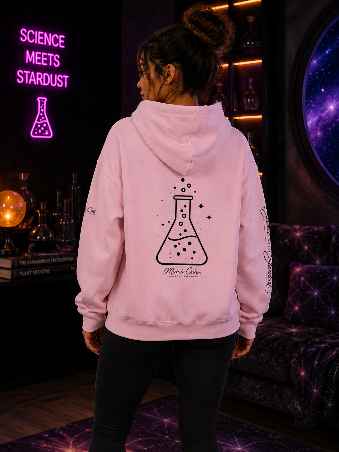 Lifestyle back view of a model wearing the Mandi Cruz Media Science Meets Stardust™ heavyweight hoodie featuring the full cosmic beaker artwork.